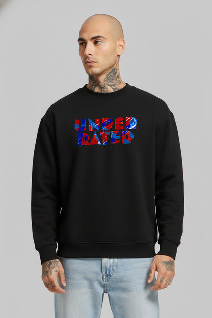 Man wearing a black “Underrated Originals” crewneck sweatshirt layered over a white collared shirt, paired with light blue jeans, standing against a plain grey background.