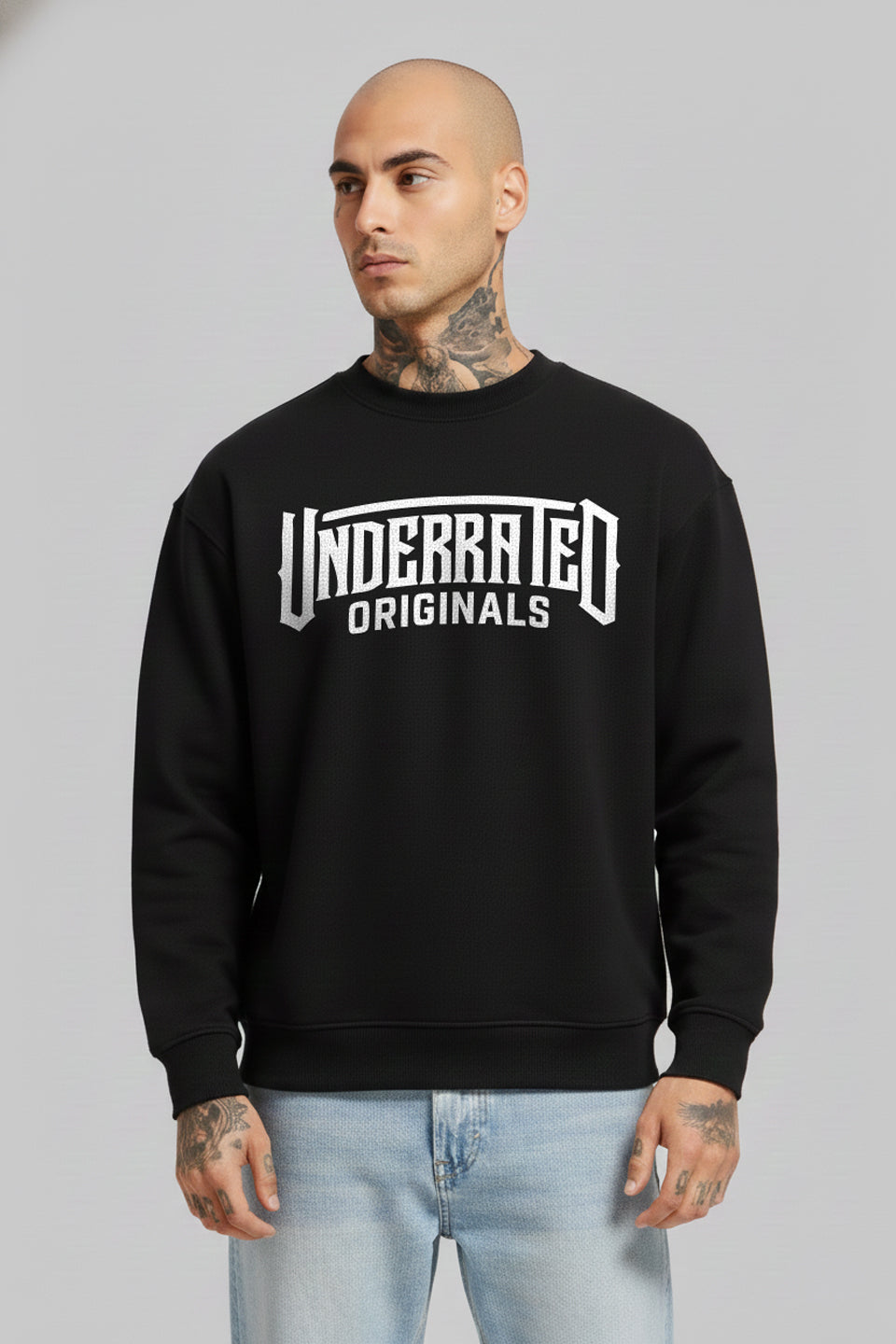 Man wearing a black Underrated Club Originals crewneck sweatshirt layered over a white collared shirt, 