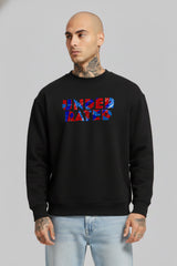 Man wearing a black “Underrated Originals” crewneck sweatshirt layered over a white collared shirt, paired with light blue jeans, standing against a plain grey background.