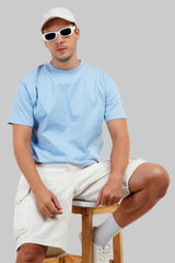 Light blue t-shirt model sunglasses seated white sneakers jeans summer streetwear Underrated Club.
