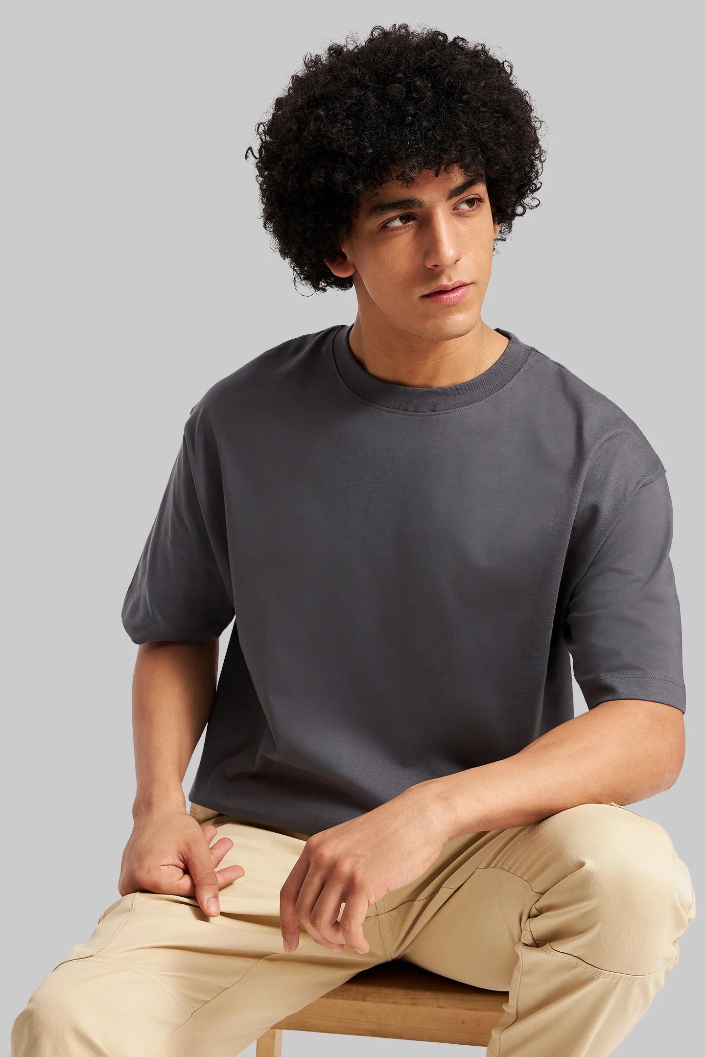 Gray t-shirt afro model relaxed seated pose jeans everyday casual wear Underrated Club men.
