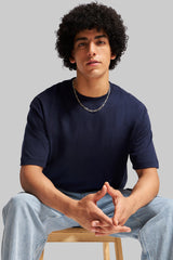 Navy blue short sleeve t-shirt afro model seated on chair blue jeans Underrated Club streetwear.
