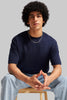 Navy blue short sleeve t-shirt afro model seated on chair blue jeans Underrated Club streetwear.
