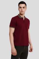 Front view of a man wearing a maroon polo shirt with a patterned collar and dark trousers.
