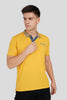 A man in a yellow polo shirt with a blue and white patterned collar adjusting his shirt.