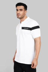 A man in a white polo shirt featuring a black graphic chest band and matching black striped sleeve cuffs.
