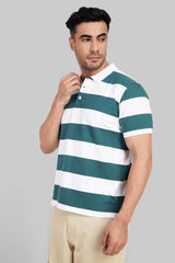 A man with dark hair wearing a teal and white horizontally striped polo shirt, adjusting his collar.