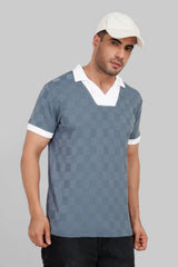 A man wearing a grey and white patterned polo shirt with a white collar and a matching white cap.
