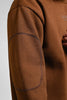 Close-up of brown men’s sweatshirt sleeve showing reinforced elbow patch and premium fabric texture.