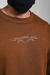 Close-up of brown men’s sweatshirt featuring subtle chest logo print and ribbed crew neck design.