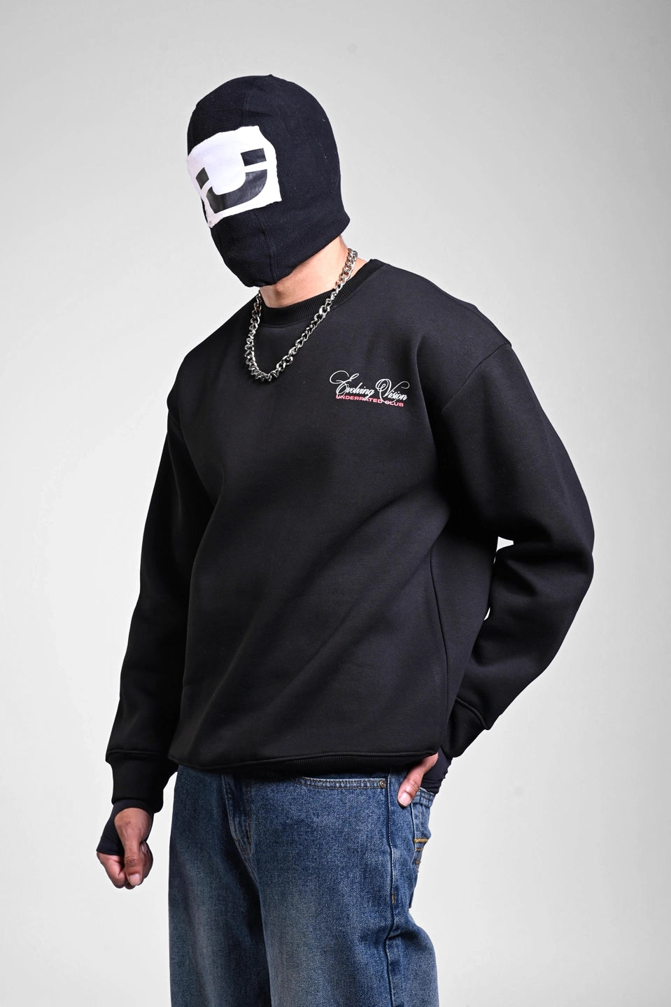 Person in a black sweatshirt featuring white cursive "Evolving Vision" text on the chest and a silver chain necklace.