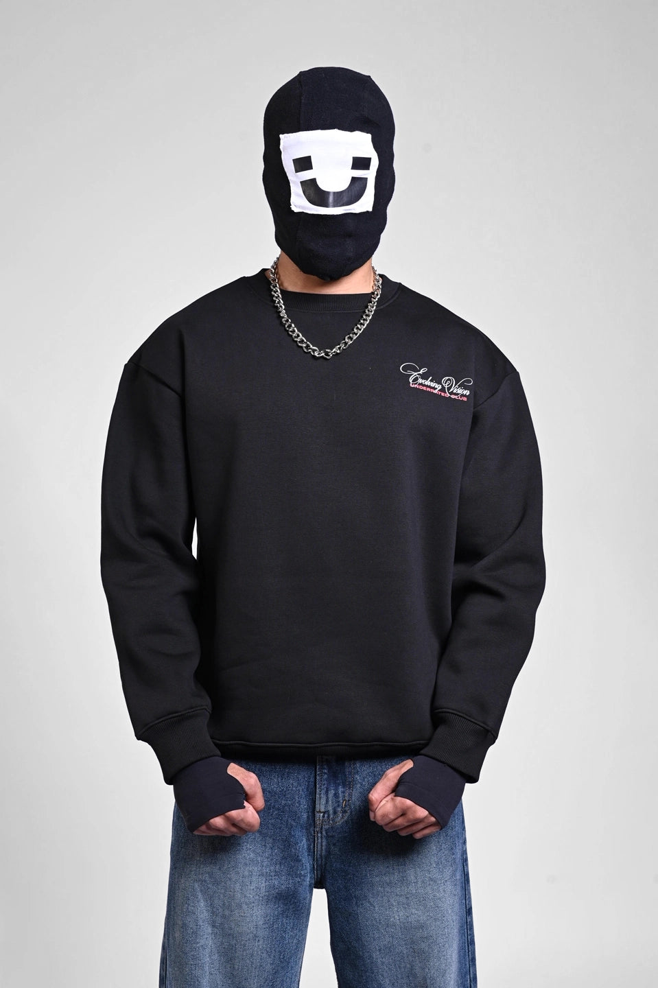 Person wearing a black "Evolving Vision" sweatshirt, a silver chain, and a graphic balaclava.