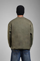 Rear view of a person wearing an olive green oversized sweatshirt, a black beanie, and blue jeans.