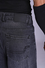 Close-up of dark grey acid-wash denim back pocket and waistband.