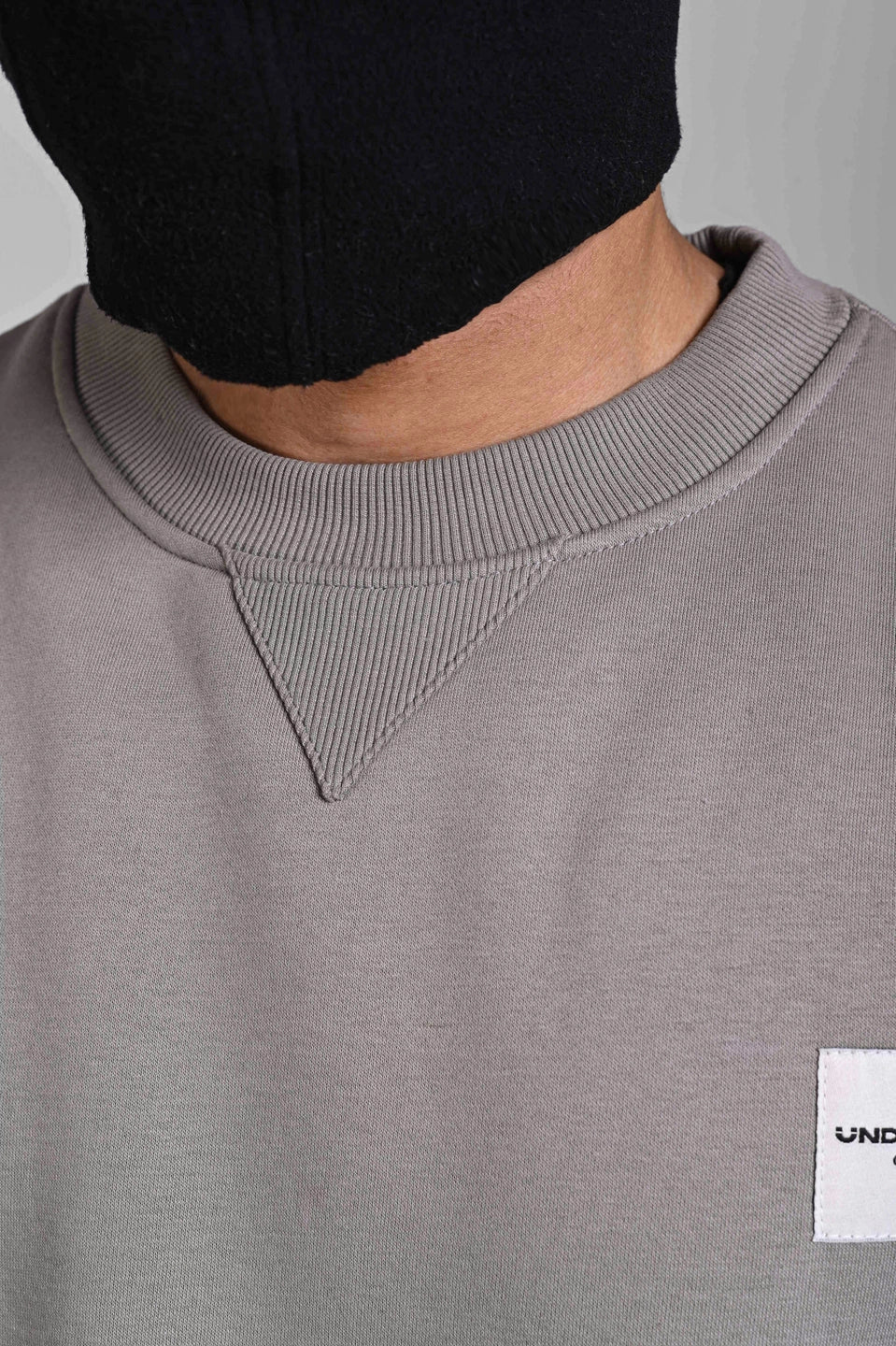 Close-up of men’s grey sweatshirt showing ribbed crew neck collar and premium fabric detailing.