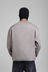 Back view of a person wearing an oversized grey sweatshirt and dark grey baggy jeans with a black beanie.