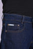 Front view close-up of dark indigo blue denim featuring a branded pocket tag.