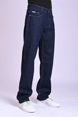 Side view of a person wearing baggy dark indigo blue jeans and white sneakers.