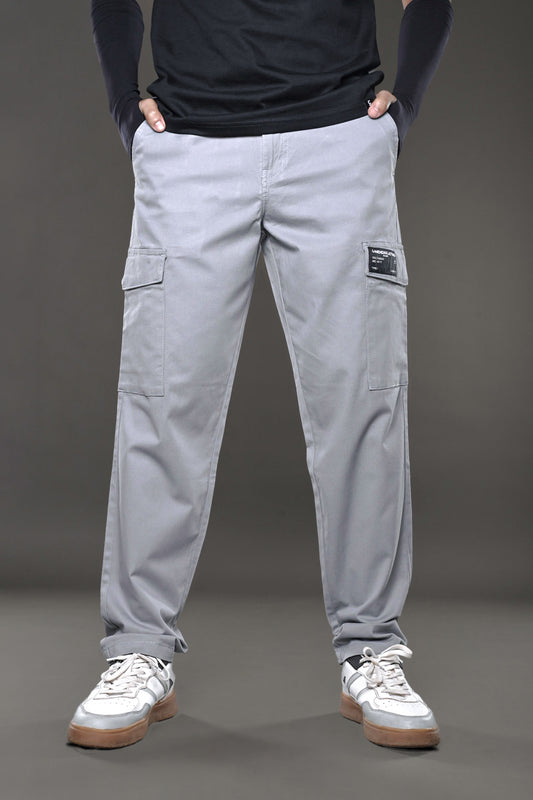 Men’s light grey cargo pants with multiple side pockets and black UNDERRATED label, styled with black top.