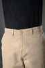 Close-up of beige UNDERRATED cargo pants waistband on model wearing black t-shirt, featuring button closure and drawstring details against grey background.
