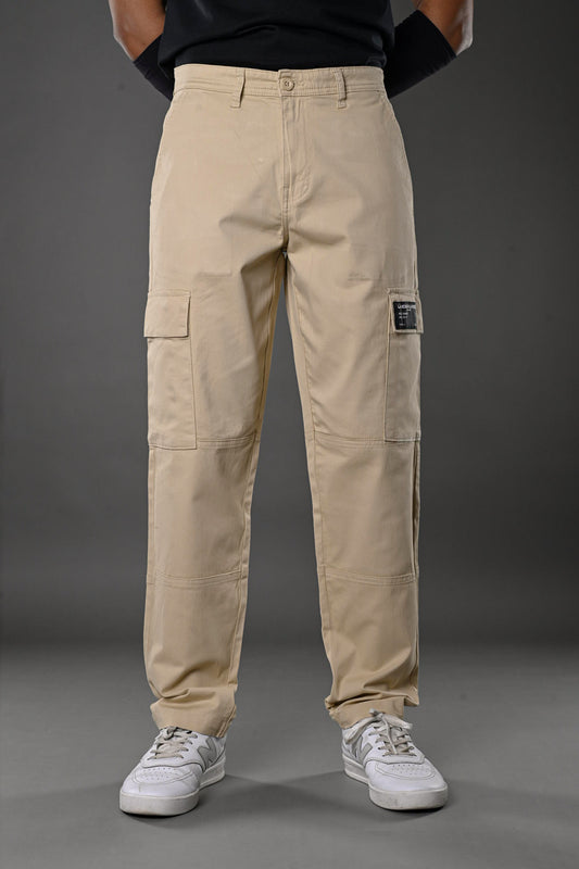 Beige UNDERRATED cargo pants waist detail on model in black top, hand in pocket, streetwear style for men.
