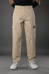 Beige UNDERRATED cargo pants waist detail on model in black top, hand in pocket, streetwear style for men.
