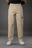 Beige UNDERRATED cargo pants waist detail on model in black top, hand in pocket, streetwear style for men.
