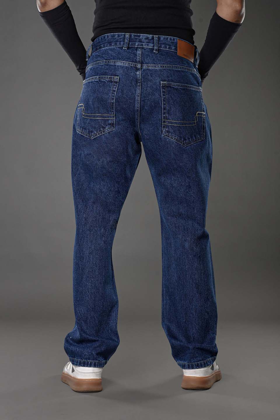 Man close-up detail dark blue jeans branded pocket and belt loops.
