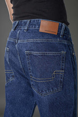 Man left side profile dark blue slim fit jeans, clean studio lighting.

