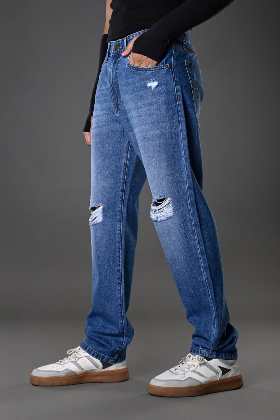 Underrated Club men's light wash ripped jeans side profile knee tears casual streetwear model white sneakers product image.
