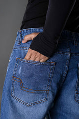 Underrated Club ripped blue jeans hip pocket closeup hand in pocket distressed denim men's streetwear detail shot.
