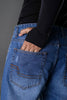 Underrated Club ripped blue jeans hip pocket closeup hand in pocket distressed denim men's streetwear detail shot.
