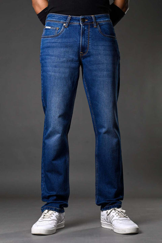 Close-up blue slim-fit jeans on male model black tank top arm cuffs white sneakers streetwear style.
