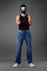Full-body man wearing white smiley balaclava black tank top slim blue jeans white sneakers gray background.
