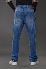 Rear full view man in light blue relaxed fit jeans black top arm cuffs white sneakers gray background Underrated Club denim.
