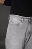 Underrated Club baggy jeans front pocket brass rivets light gray wash closeup branded apparel.
