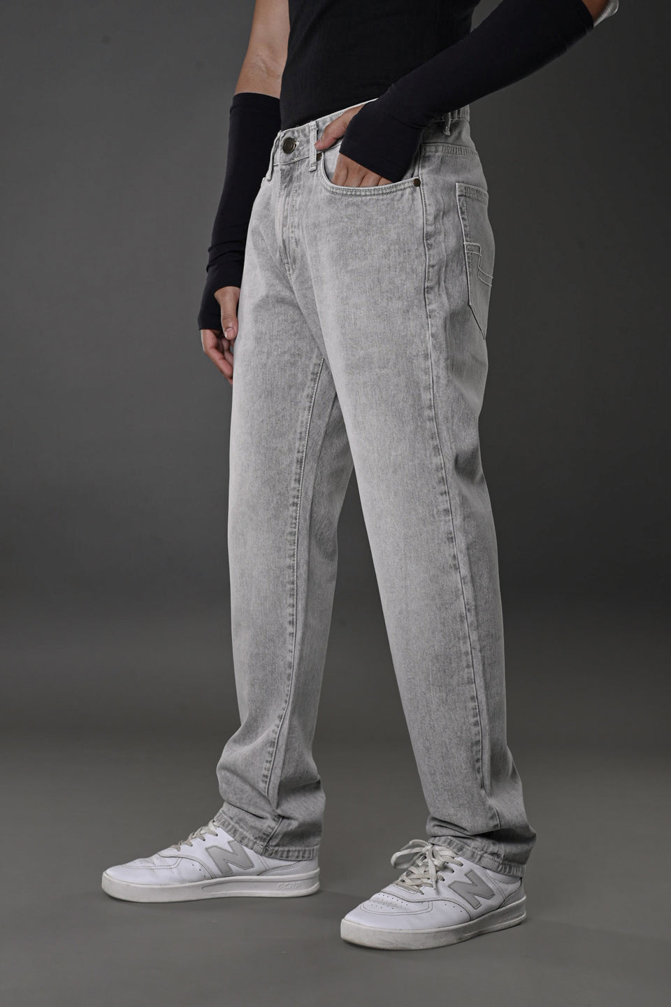 Grey baggy jeans side view hands pockets black long sleeve cuffs white sneakers men's streetwear Underrated Club.
