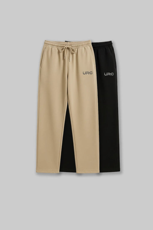 Flat lay of two pairs of relaxed-fit "URC" drawstring trousers.
