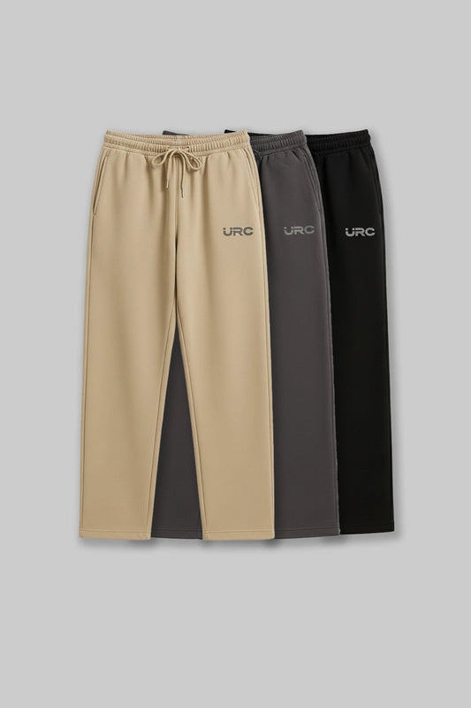 A man wearing beige relaxed-fit "URC" drawstring trousers paired with olive green sneakers.