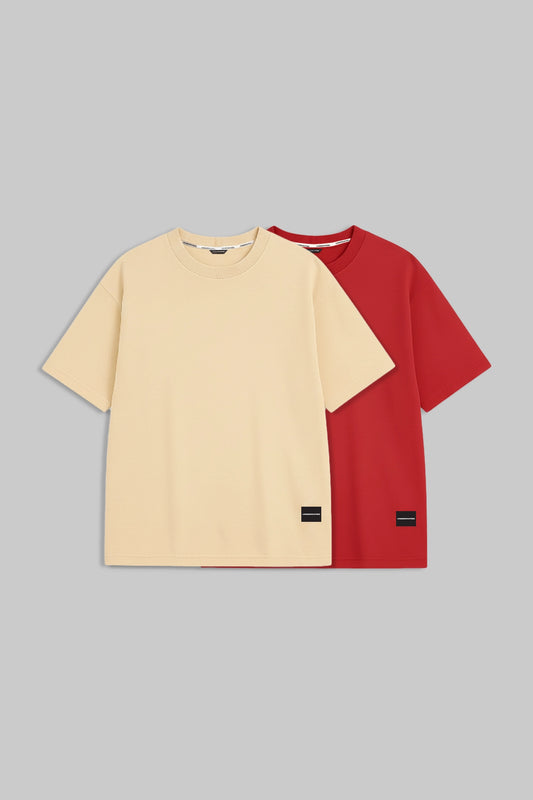 Two short-sleeve crewneck t-shirts displayed flat against a solid gray background. The front t-shirt is a light cream/beige color, and the t-shirt behind it is a vibrant red.