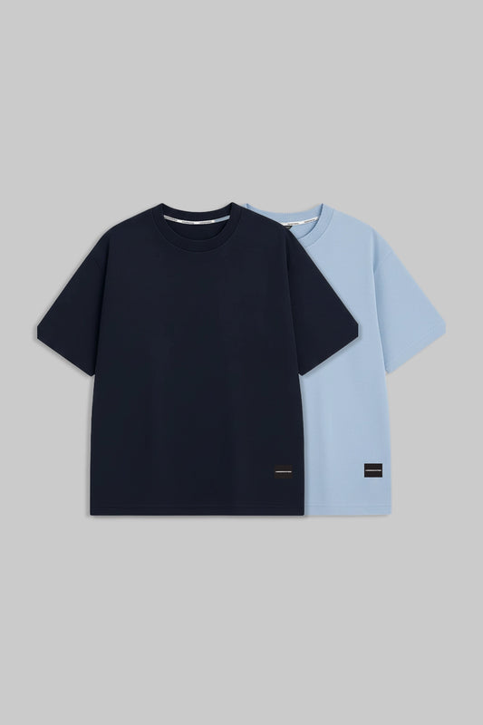 Two short-sleeve crew-neck t-shirts displayed flat against a solid gray background. The front t-shirt is solid navy blue, and the t-shirt behind it is light blue.