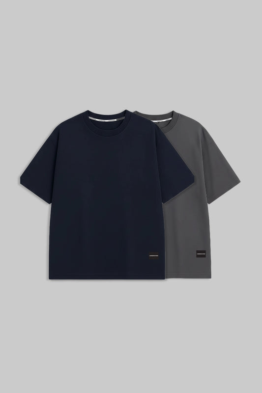 Two short-sleeve crew-neck t-shirts displayed against a solid gray background. The front t-shirt is dark navy blue, and the t-shirt behind it is dark gray.