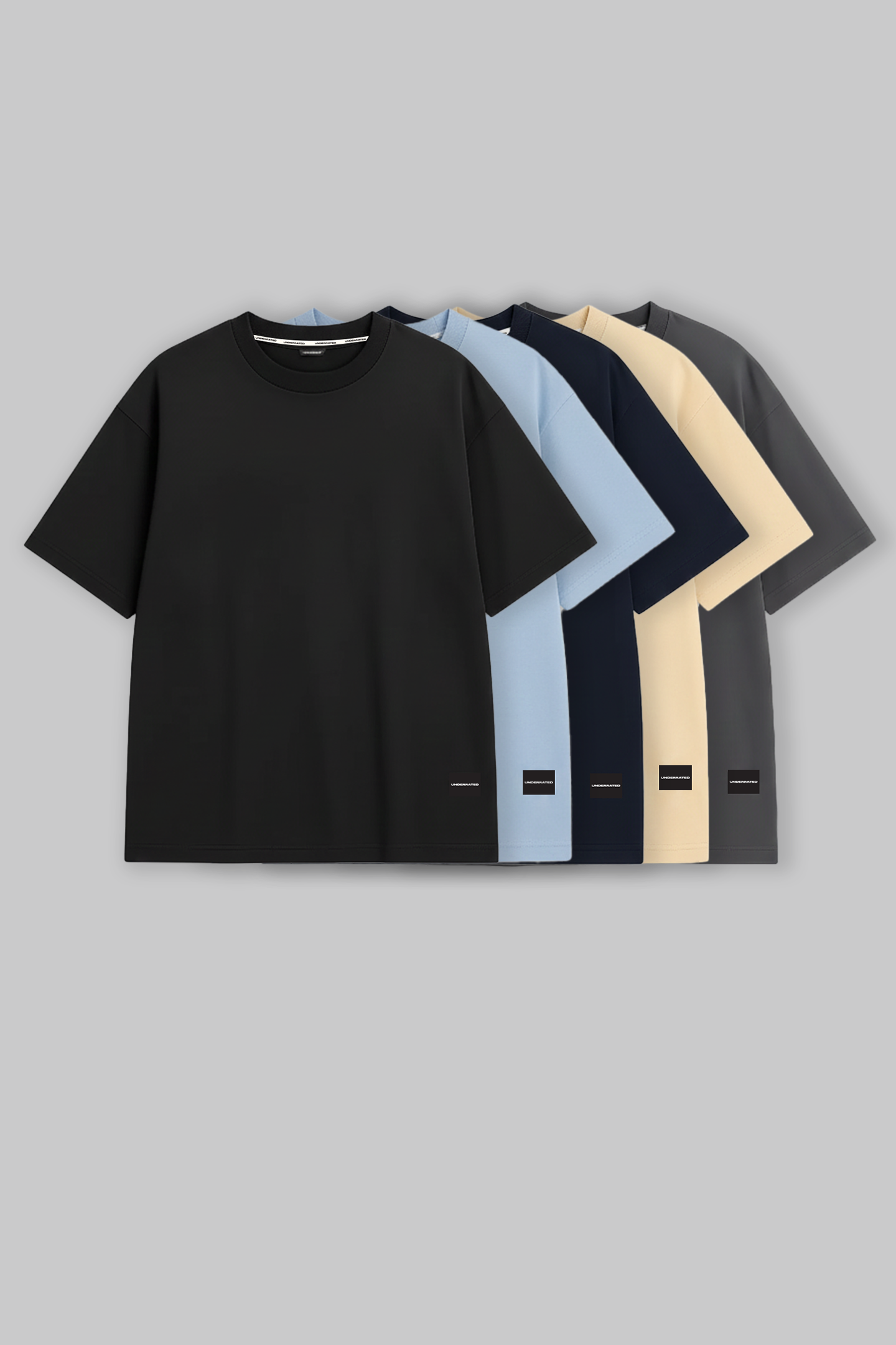 UNDERRATED oversized t-shirts quintet in black, light blue, navy, beige, and grey colors with brand tags against grey background - men's streetwear collection.
