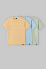 Pack of three men's crew neck t‑shirts in beige, mint green, and light blue laid flat on a light background.
