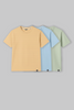 Pack of three men's crew neck t‑shirts in beige, mint green, and light blue laid flat on a light background.
