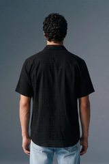 Person wearing a black shirt and light blue jeans against a gray background