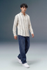 Man wearing a striped shirt and jeans on a gray background