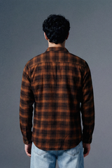 Person wearing a brown plaid shirt against a gray background