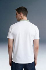 Rear view from the waist up of a man looking over his left shoulder, showing the back of a white polo shirt with a contrasting olive green collar.