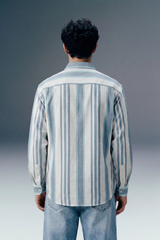 Person wearing a striped shirt and jeans from behind on a gradient background